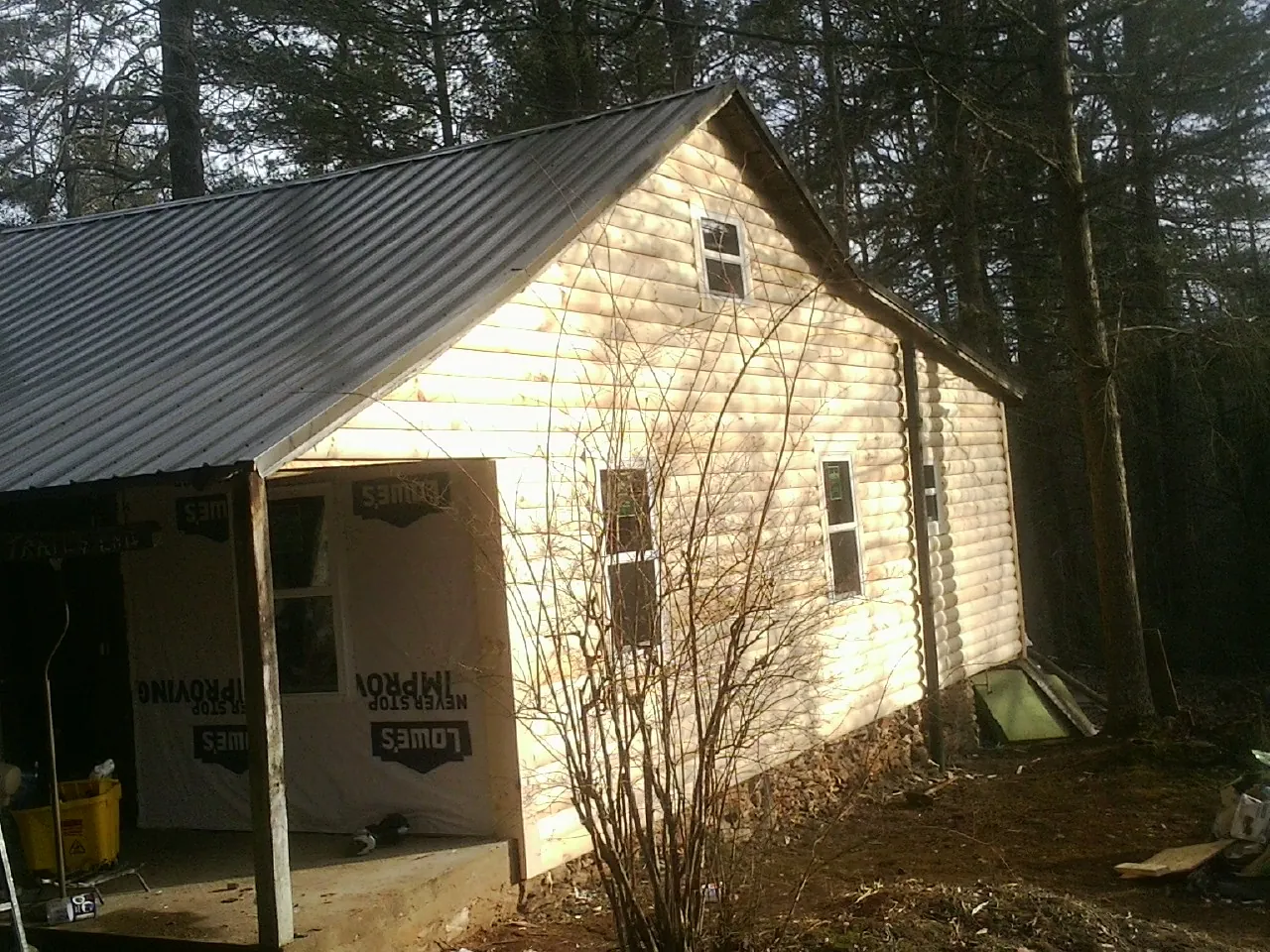 Log siding gable end under a dark metal roof edge in Dornsife