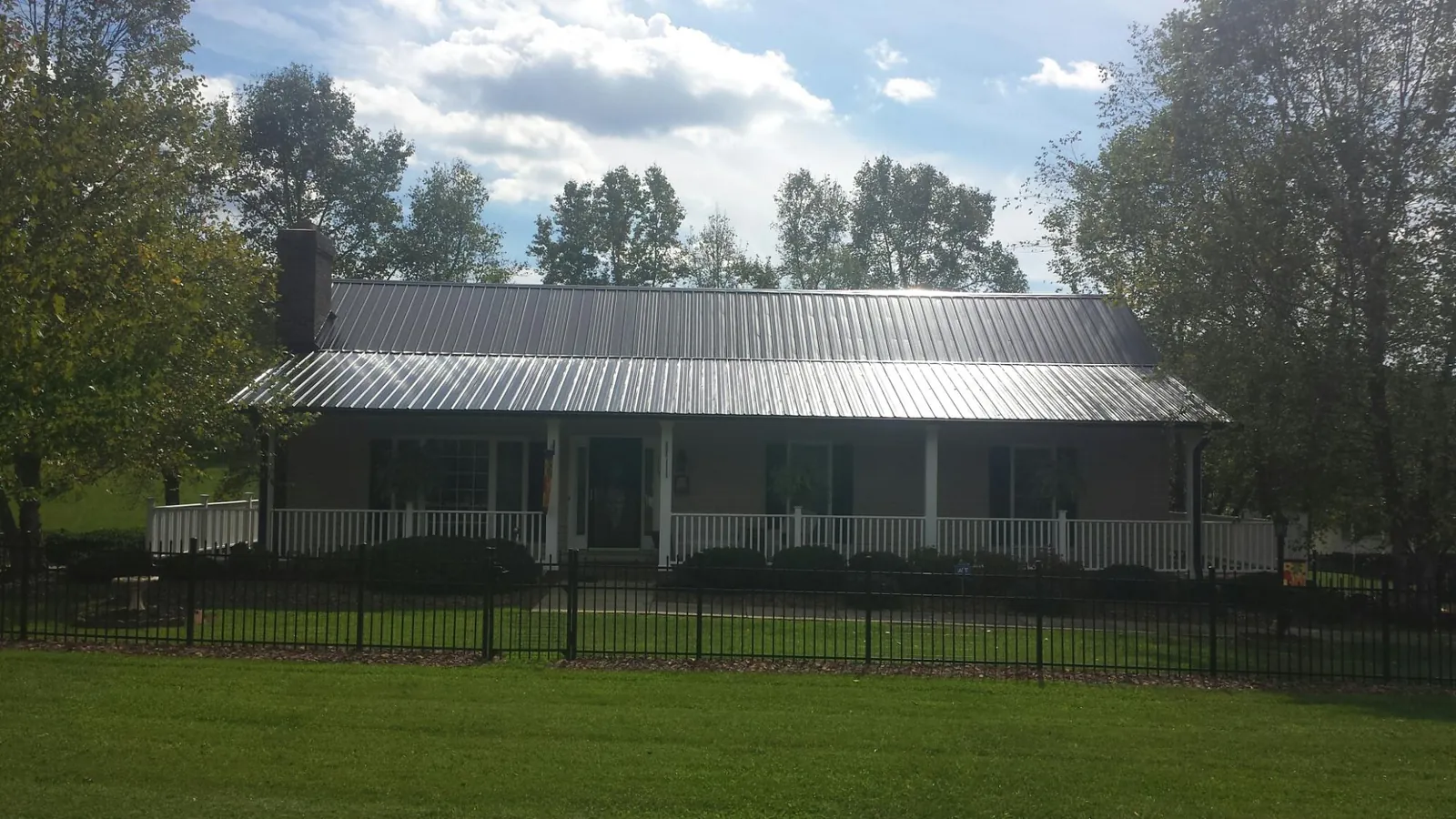 Gray metal roof on a brick ranch with a full width front porch — Gutter Guard Installation work by our crew in Dornsife