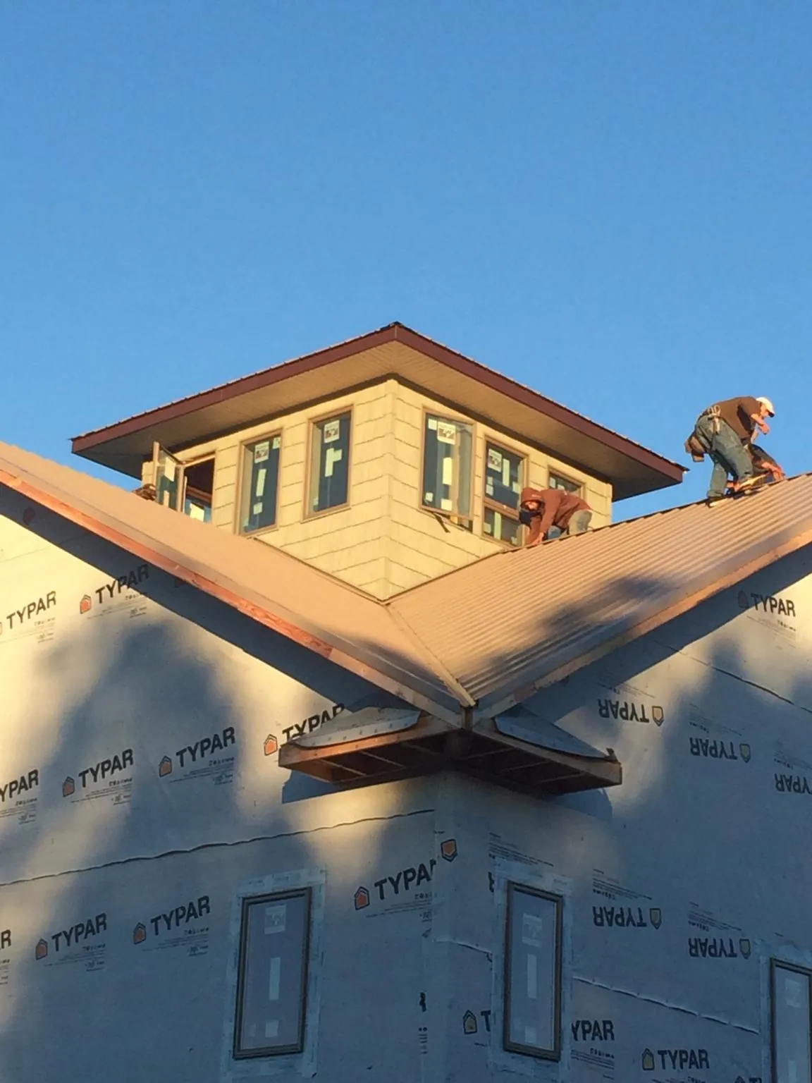 Roofers working around a rooftop cupola on a new metal roof at sunset — Roof Waterproofing in Dornsife by Roofing Brothers